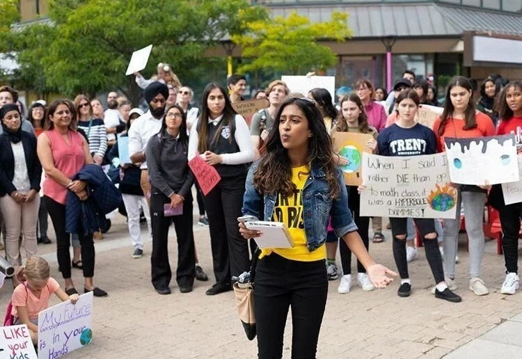 Woman leads climate action rally, surrounded by group of young people.