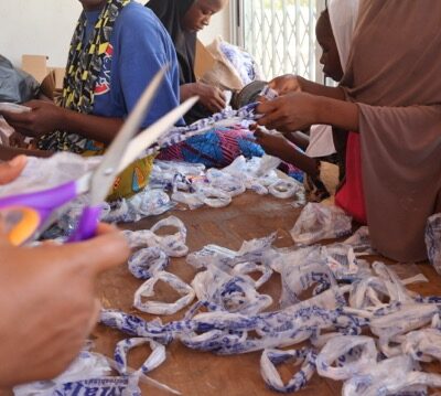 A group of young people cutting plastic bags to create rope.