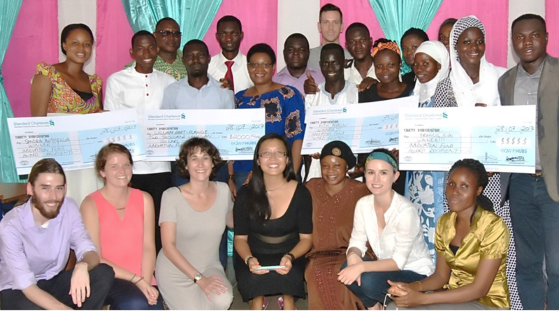 Screen-Shot-2017-11-27-at-6.24.55-PM A diverse group poses indoors with three large ceremonial checks and colorful pink and teal curtains behind them.